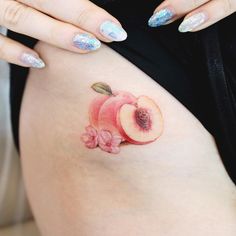 a woman's stomach with an apple and flower tattoo on the side of her belly