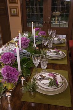 the table is set with place settings and flowers on each plate, along with candles