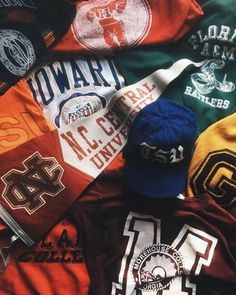 many different colored baseball caps laying on top of each other, all with the same team's logos