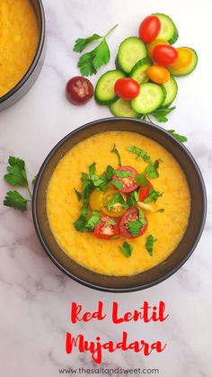 two bowls filled with soup next to cucumbers and tomatoes on a white table