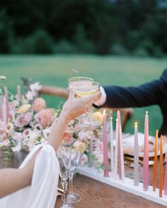 a man and woman toasting with wine glasses in front of candles on a table