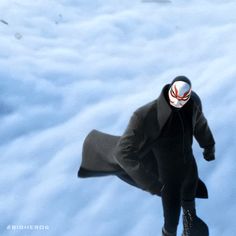 a person wearing a mask and coat walking in the snow