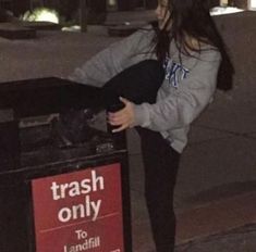 a woman standing next to a trash can