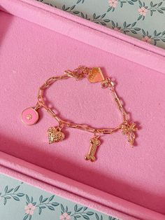 a pink box with a gold charm bracelet in it