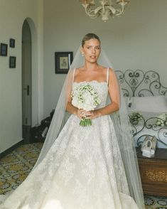 a woman in a wedding dress standing next to a chandelier