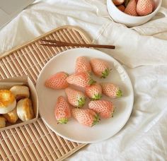 strawberries and bananas are on a white plate next to a bowl of oranges