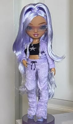 the doll is wearing purple pants and a crop top with silver sequins on it