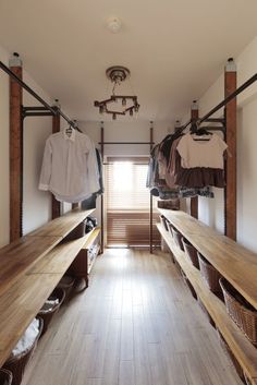 a long hallway with wooden benches and hanging clothes