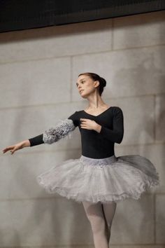 a young ballerina wearing a tutu and holding her arms out to the side