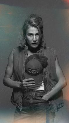 black and white photograph of a woman holding a baseball cap in her right hand, wearing denim vest