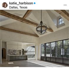 the inside of a house with large windows and wood beams on the ceiling is shown