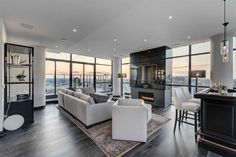 a living room filled with furniture next to tall windows and a fire place in the corner