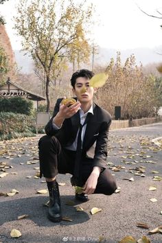 a man kneeling down holding a yellow frisbee in his hand while wearing a suit and tie