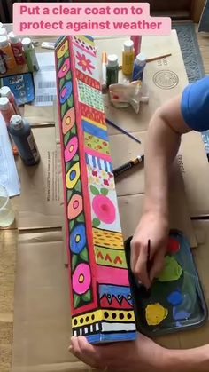 a person is working on an art project with acrylic paint and cardboard boxes