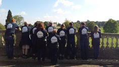 a group of people standing next to each other near a stone wall with writing on them