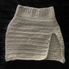 a crocheted white skirt is laying on a black surface, with the bottom part folded up