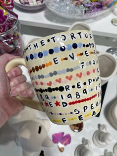 a person holding a coffee mug with letters on it