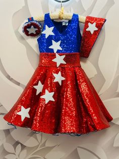 a red, white and blue dress with stars on it is hanging from a wall