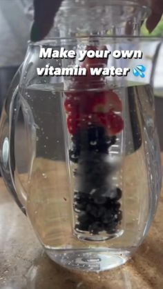 a person is pouring water into a glass container with berries in it and the words make your own vitamin water