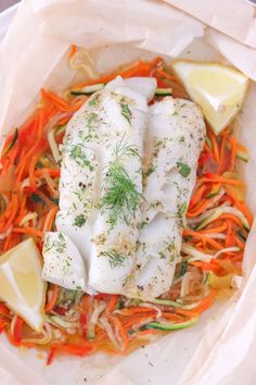 a fish dish with carrots, cabbage and lemon wedges