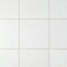 a white tiled wall with small speckles on the top and bottom tiles in different sizes