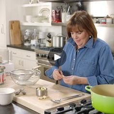 a woman standing in a kitchen preparing food on top of a wooden cutting board with utensils