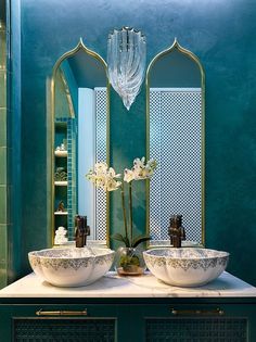 two white bowls sitting on top of a counter next to a vase with flowers in it