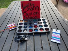 there is a cupcake pan with buttons on it and a sign that says lucky charm creation station