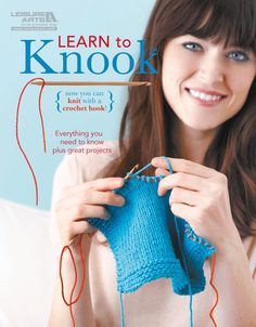 a woman smiling while holding up a blue knitted object