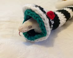 a toy rat in a knitted sweater on a white tablecloth next to a toothbrush