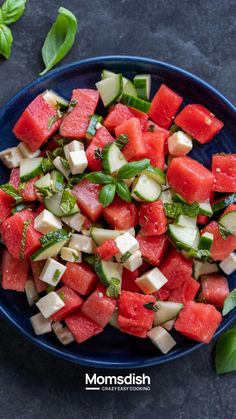 watermelon and cucumber salad in a blue bowl with basil on the side