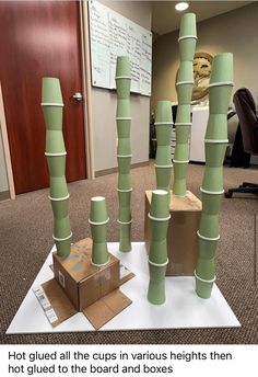 there are many stacks of green cups on the floor in an office cubicle that is made out of cardboard boxes