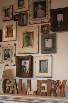 a wall filled with framed pictures and wooden letters