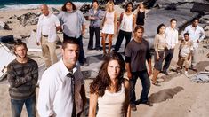 a group of people standing on top of a sandy beach next to the ocean,