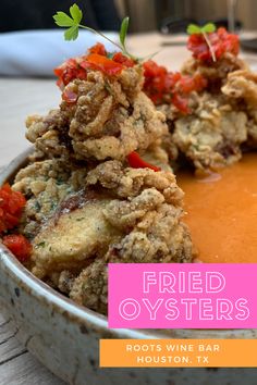 fried oysters are served in a white bowl with orange sauce and garnishes