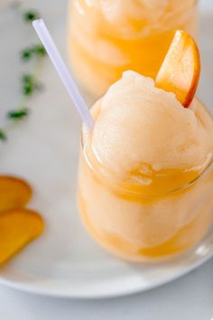 two glasses filled with ice cream and orange slices on a white plate next to carrots