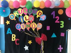 balloons and streamers decorate the entrance to a school's birthday party with black backdrop