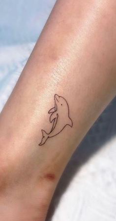 a small dolphin tattoo on the ankle is shown in black ink, and it appears to be an outline