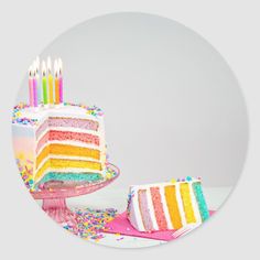 a slice of rainbow cake with lit candles