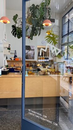 the inside of a restaurant with plants hanging from it's ceiling and on the counter