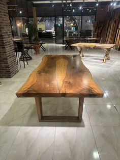 a large wooden table sitting on top of a white tiled floor next to tables and chairs