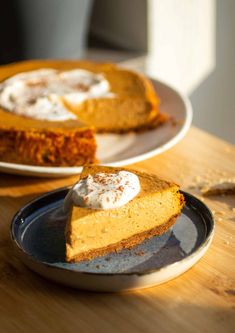 two plates with slices of pumpkin cheesecake on them and one slice has whipped cream