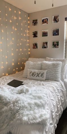 a bed with white sheets and pillows in a room decorated with string lights on the wall