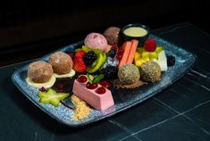 a blue plate topped with fruit and desserts on top of a black countertop