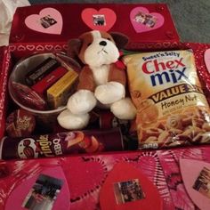 a teddy bear sitting on top of a red box filled with snacks and candys