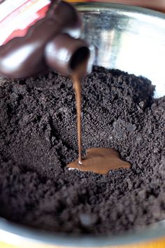 someone is pouring chocolate into a bowl full of dirt