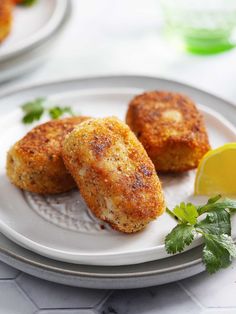 two crab cakes on a plate with lemon wedges and parsley garnish