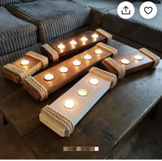 candles are arranged in the shape of boats on a table next to couches and pillows