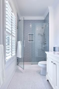 a bathroom with a toilet, sink and shower in it's stall area next to a window