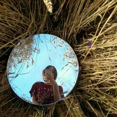 a person taking a selfie in front of a mirror on the grass covered ground